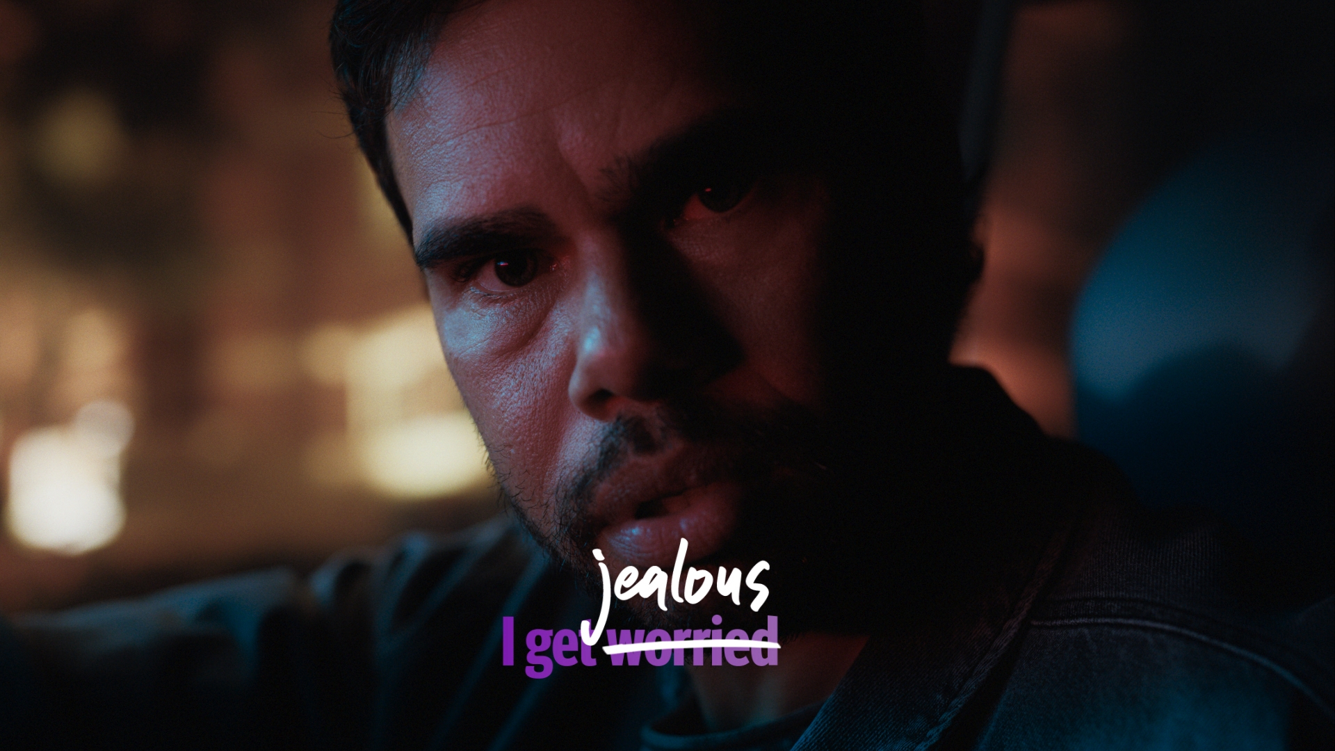 Close-up of an adult male with a serious expression, dimly lit with purple text overlay on the lower half of the frame.