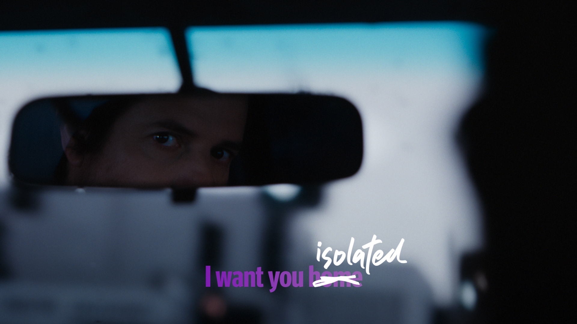 Reflection in car mirror showing adult male’s face in soft lighting, accompanied by the text 'isolated' and 'I want you home.'