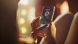 Close-up of hands holding a smartphone displaying an incoming call screen with a contact photo and heart icons.