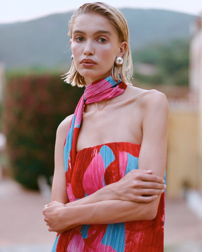Model in colorful patterned strapless dress with matching scarf and silver earrings posing outdoors
