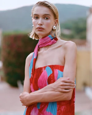 Model in colorful patterned strapless dress with matching scarf and silver earrings posing outdoors