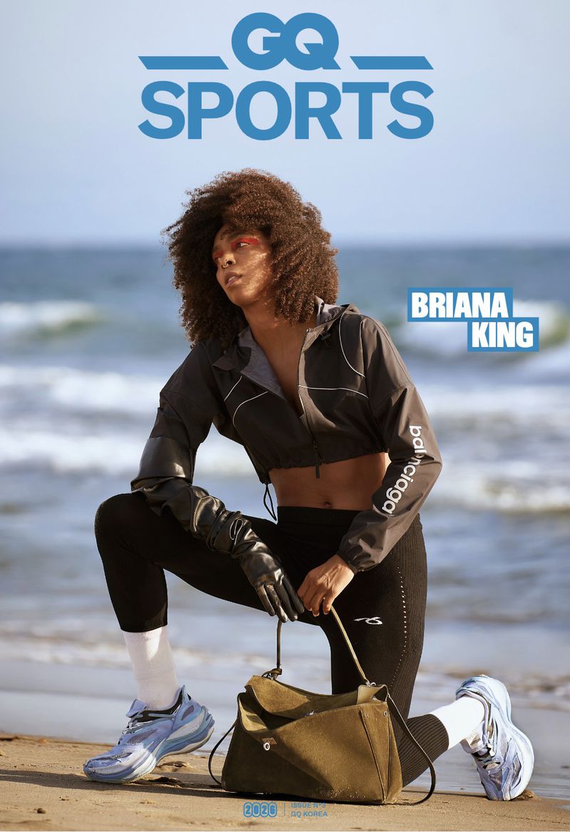 Briana King poses on a sandy beach in sportswear and sneakers with ocean and sky in the background for a GQ Sports cover.