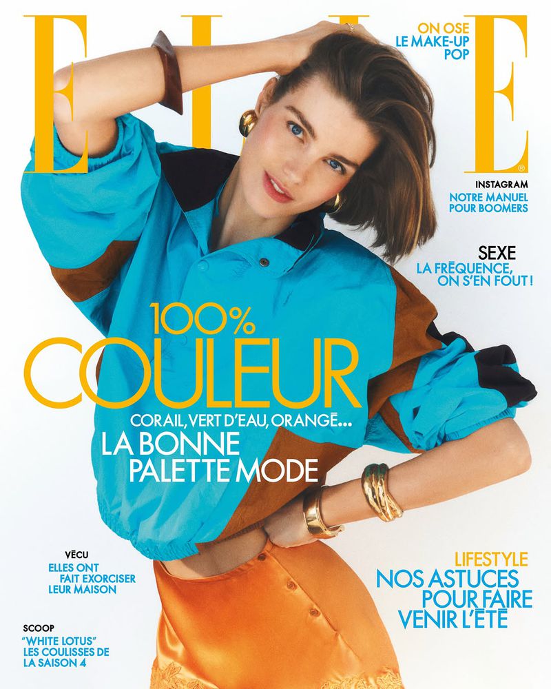 Model Luna Bijl poses for the Elle France cover in a vibrant turquoise windbreaker and orange satin skirt against a white studio sweep.