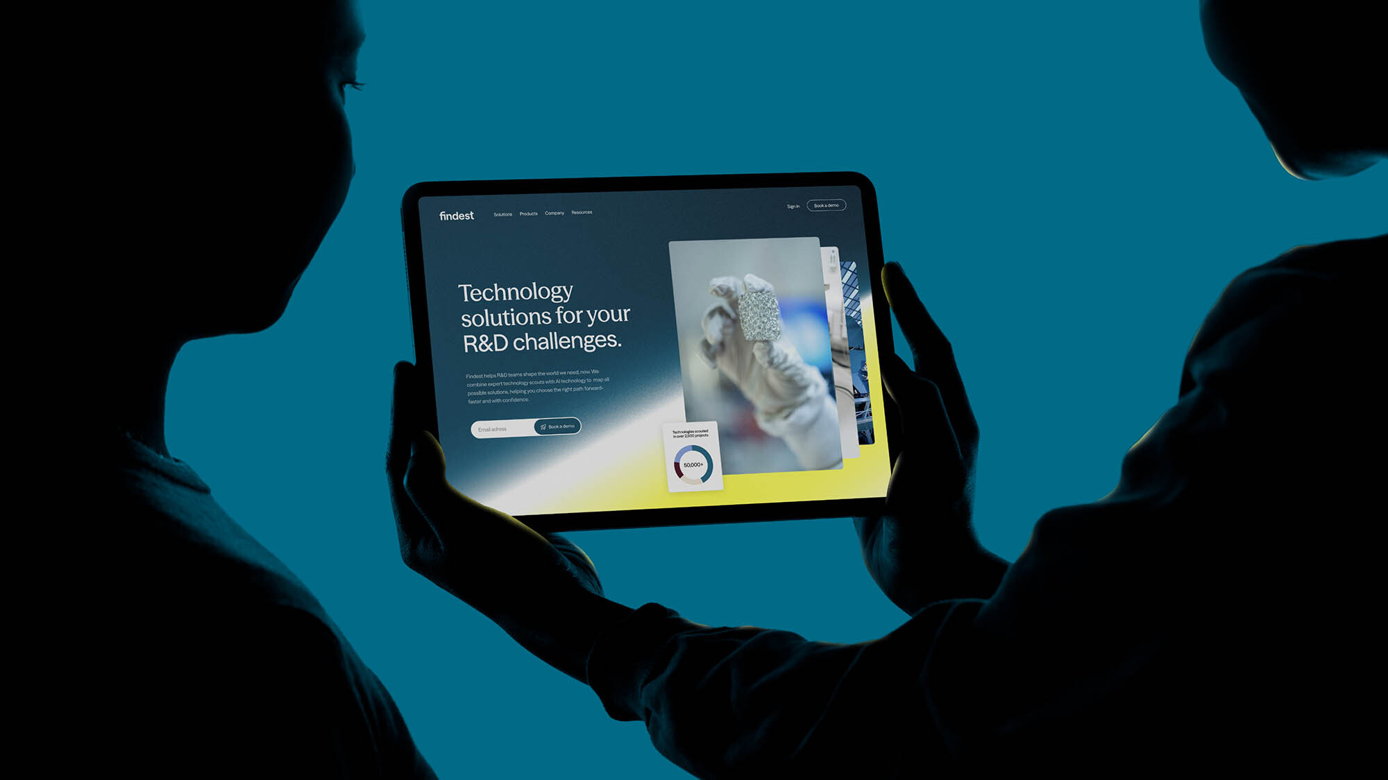 Silhouetted figures holding a tablet displaying the Findest website interface against a teal background.