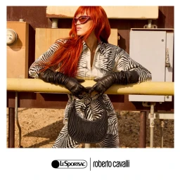 Model Kiddy Akita Lou in zebra print jumpsuit and leather gloves posing against an industrial background for LeSportsac and Roberto Cavalli