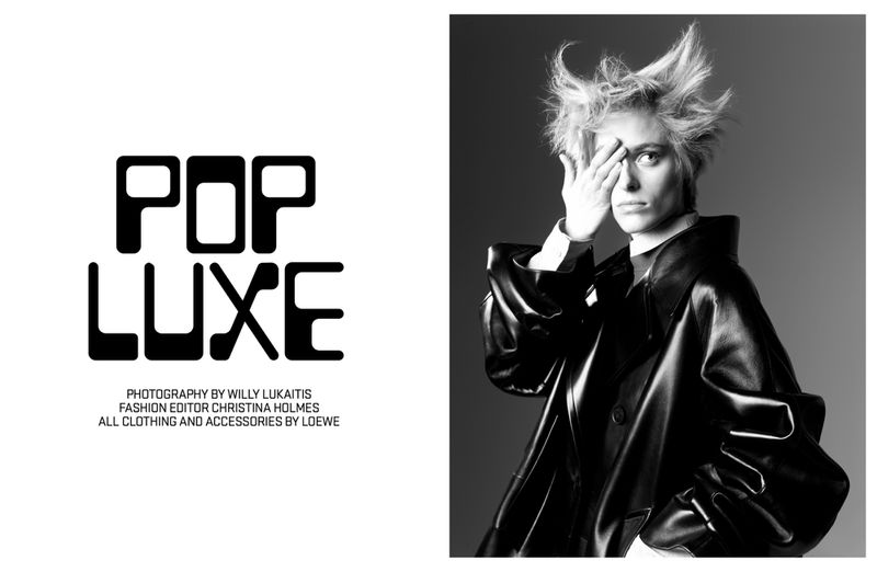 Black and white editorial portrait of a model with spiky hair covering one eye wearing a dark leather coat against a gradient background.