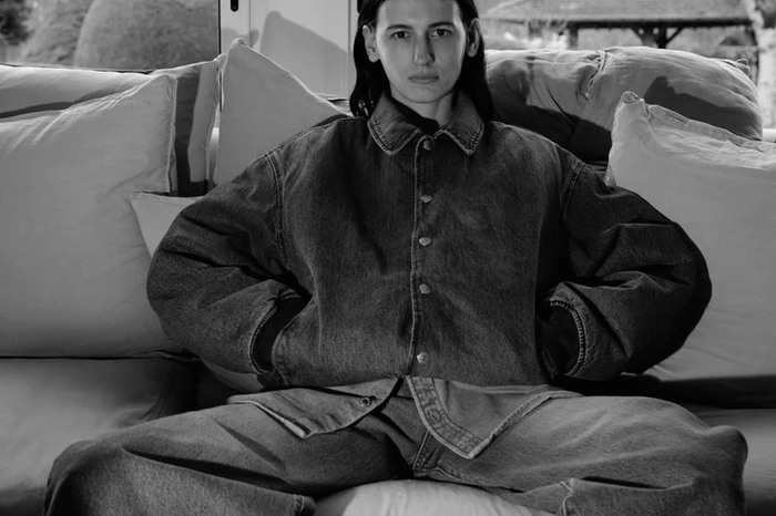 Black and white portrait of a woman seated on a sofa wearing an oversized denim jacket and jeans for Alei Journal x Levis.