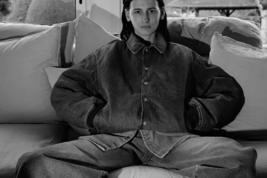Black and white portrait of a woman seated on a sofa wearing an oversized denim jacket and jeans for Alei Journal x Levis.