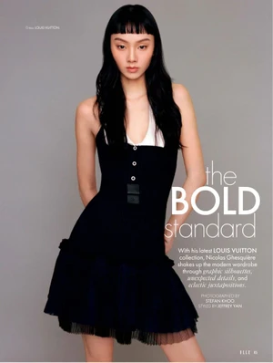 Model with long dark hair wearing a black dress against a solid grey background for Elle Singapore