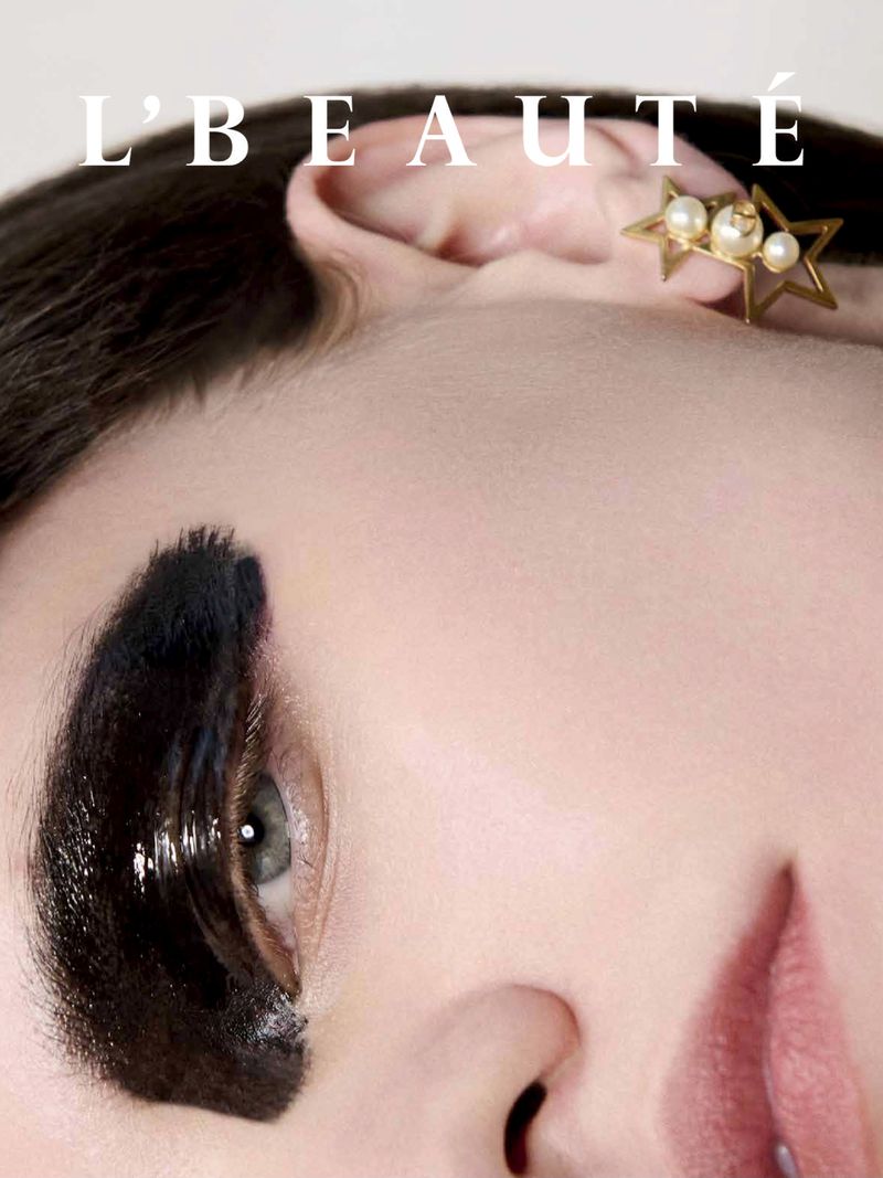 Close-up beauty shot features a woman with bold black eyeliner and a star-shaped earring, with text reading 'L'BEAUTE' at the top.