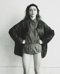 Sadie Sink wearing an oversized dark leather jacket and shorts against a plain wall for Pop Magazine