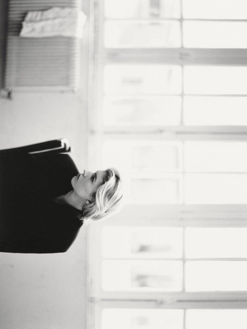 Black and white profile portrait of Camille Chifflot in a dark top with short blonde hair against a bright window.