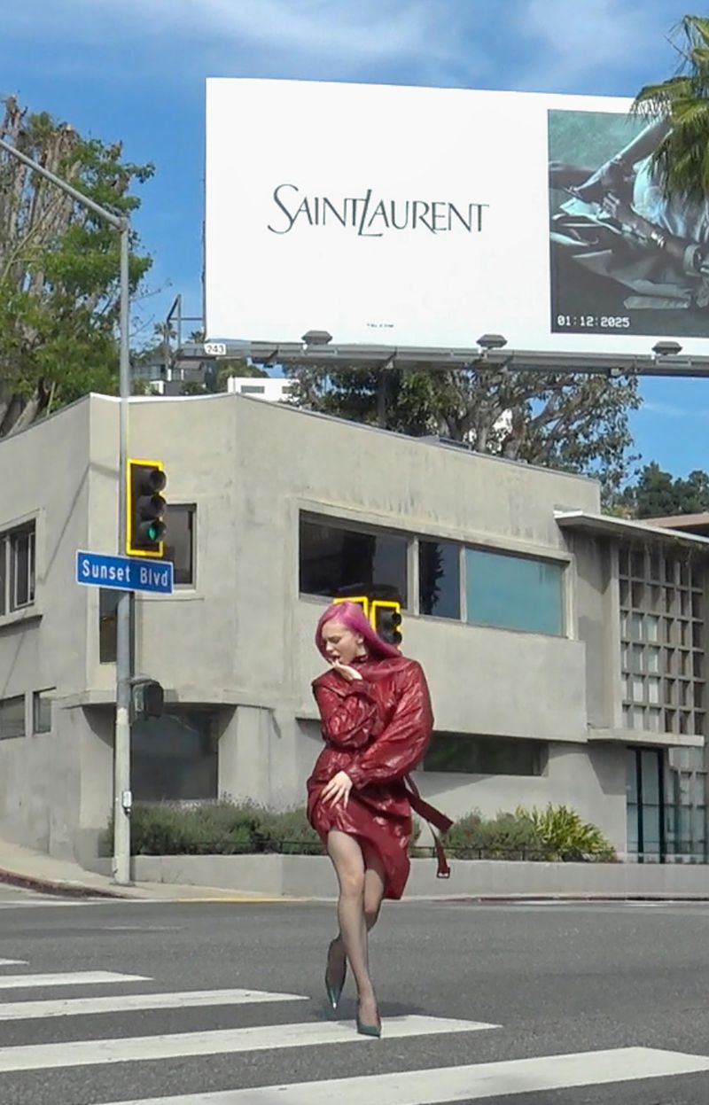 Adéla Jergová with bright pink hair posing in a crosswalk on Sunset Boulevard wearing a glossy burgundy leather trench coat dress.