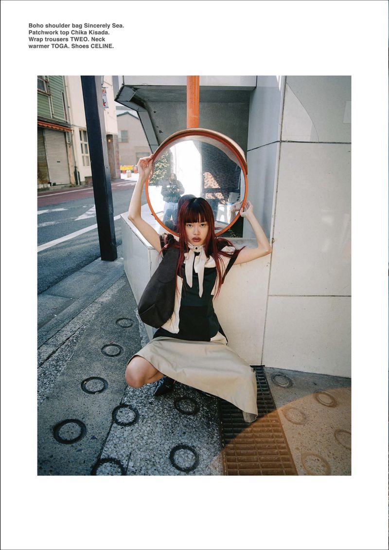 Model holding a round convex street mirror on a city sidewalk for DEW Magazine Future Bloom editorial