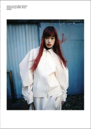 Model Yuki Beniya wearing an off-white sculptural zip jacket and skirt against a blue corrugated metal wall.