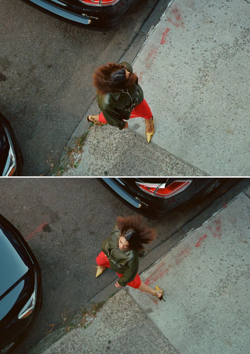 High-angle overhead view of model Aliza Jarmon walking on a sidewalk in an olive green jacket, red pants, and yellow heels.