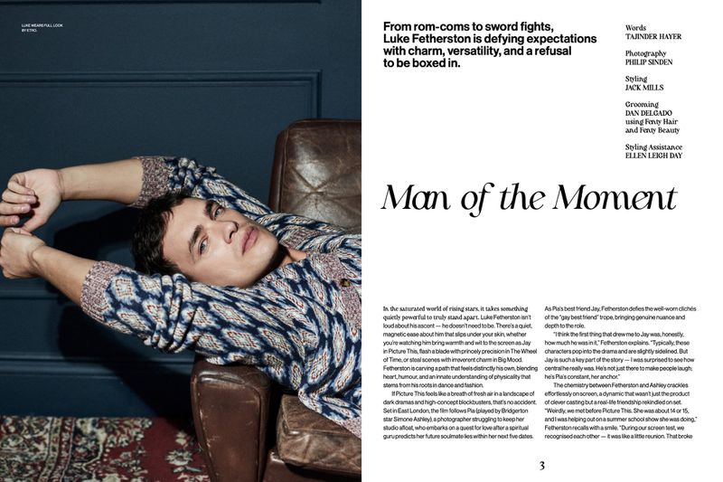 Man lying on leather chair wearing patterned sweater in fashion editorial photography indoors with dark blue wall background.