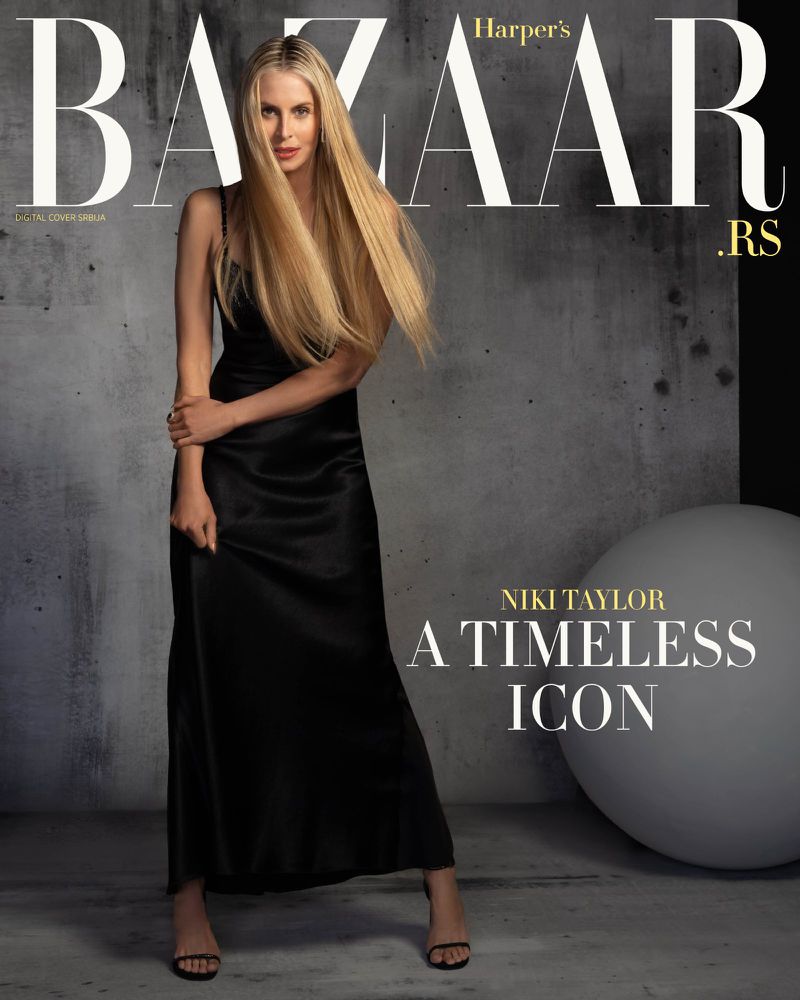 Niki Taylor posing in a black satin maxi dress and heeled sandals against a textured grey wall on a Harper's Bazaar cover.