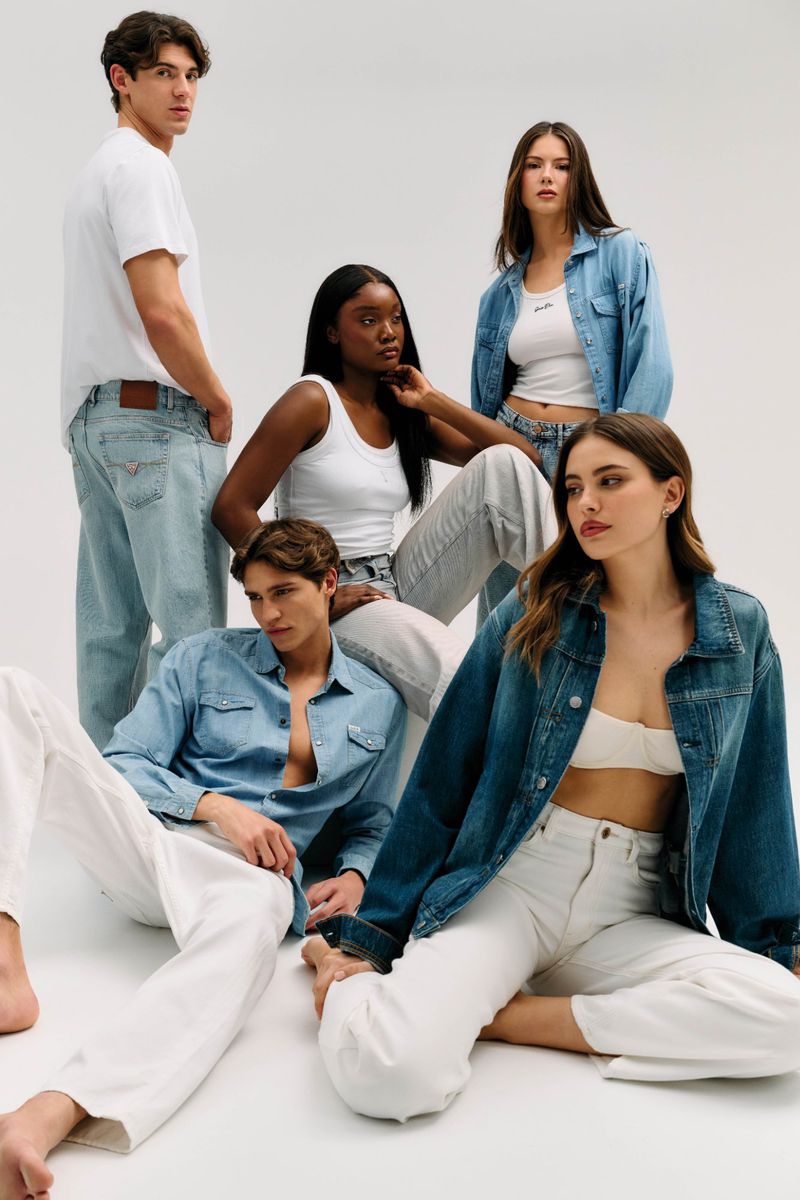 Five models posing together wearing denim jackets, jeans, and white tops against a bright white seamless background.