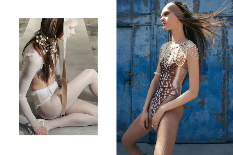 Two fashion models pose indoors with a combination of white lingerie, swimsuits, beaded collars and pearl jewelry in a studio setting.