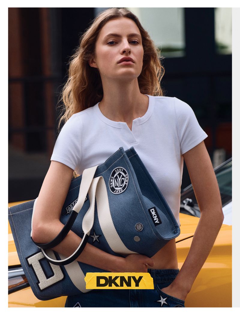 Model Felice Nova Noordhoff holding a blue denim tote bag and wearing a white cropped top next to a yellow car.