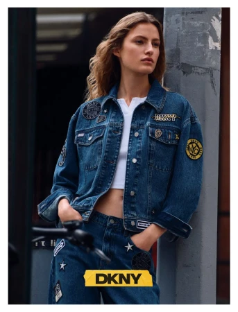 Model in patched denim jacket leaning against a concrete column outdoors