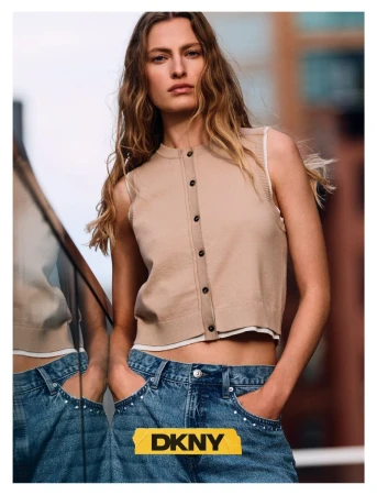 Felice Nova Noordhoff wearing a cropped beige knit vest and studded blue jeans against an urban backdrop in a DKNY campaign.