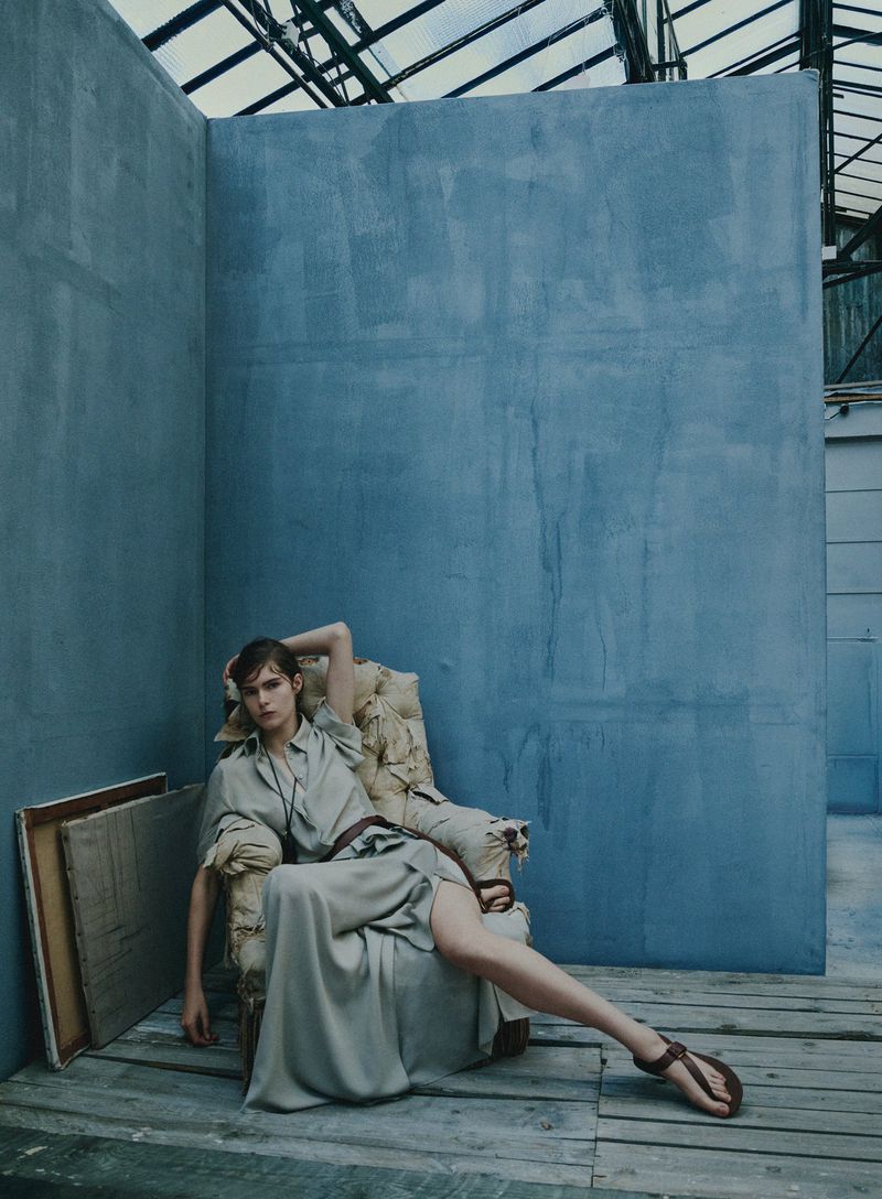 Model seated in an ornate armchair against a textured blue wall for Elle U.S. fashion editorial photography.