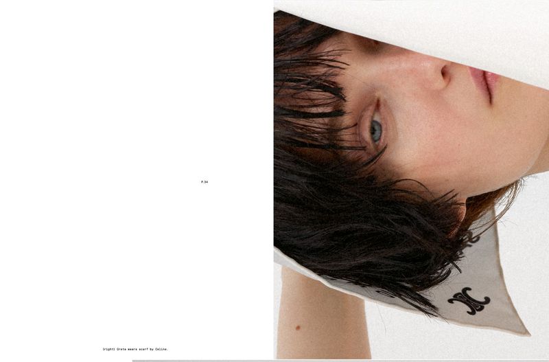 Close-up editorial portrait of model Greta Hofer looking through a white cutout while wearing a white printed Celine scarf.