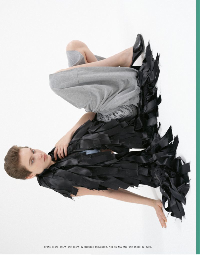 Model Greta Hofer posed on a white background wearing a shredded black ribbon piece and grey culottes for Endless Magazine.