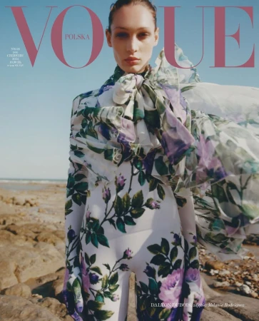 Vogue Polska cover featuring a woman in a floral patterned outfit standing on a beach with tan sand and a clear blue sky.