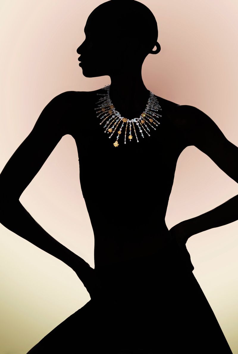 Silhouette of model Debra Shaw wearing an intricate diamond fringe necklace against a warm pale gradient background.