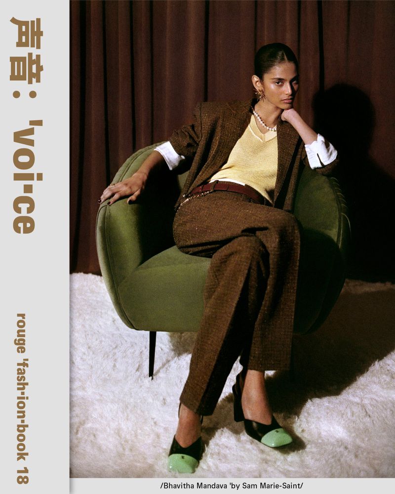 Model Bhavitha Mandava seated in a green armchair wearing a brown tweed pantsuit and two-tone heels for Rouge Fashionbook 18.
