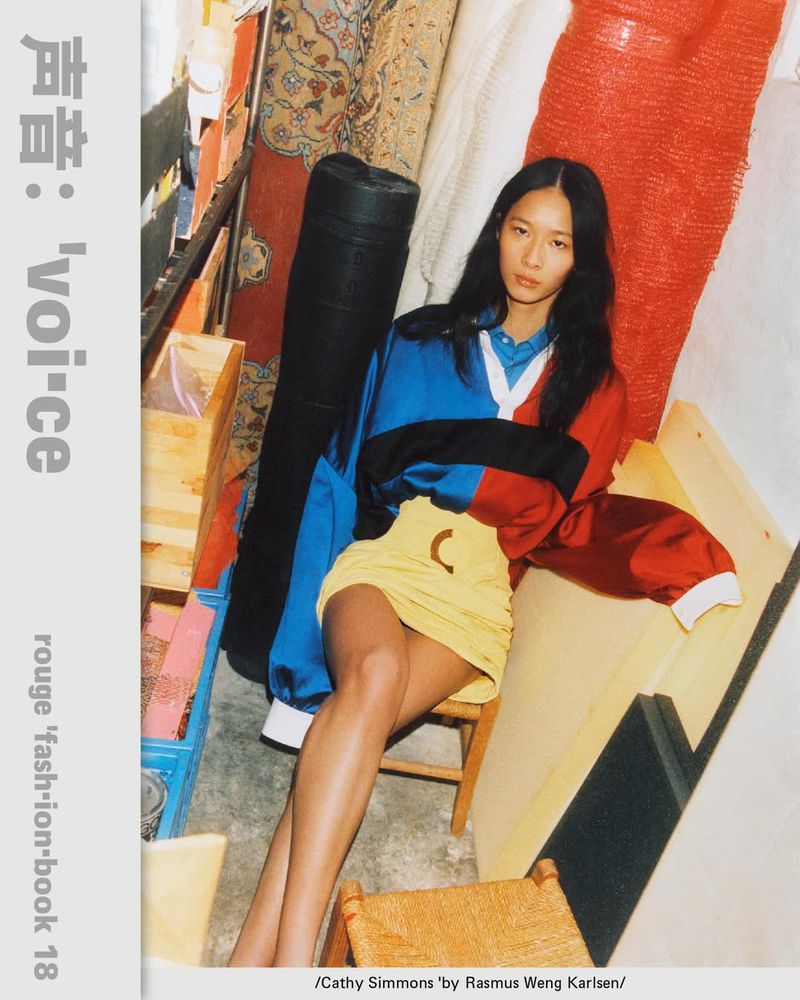 Model Cathy Simmons seated in a storage space wearing a red and blue color-blocked top and yellow mini skirt.