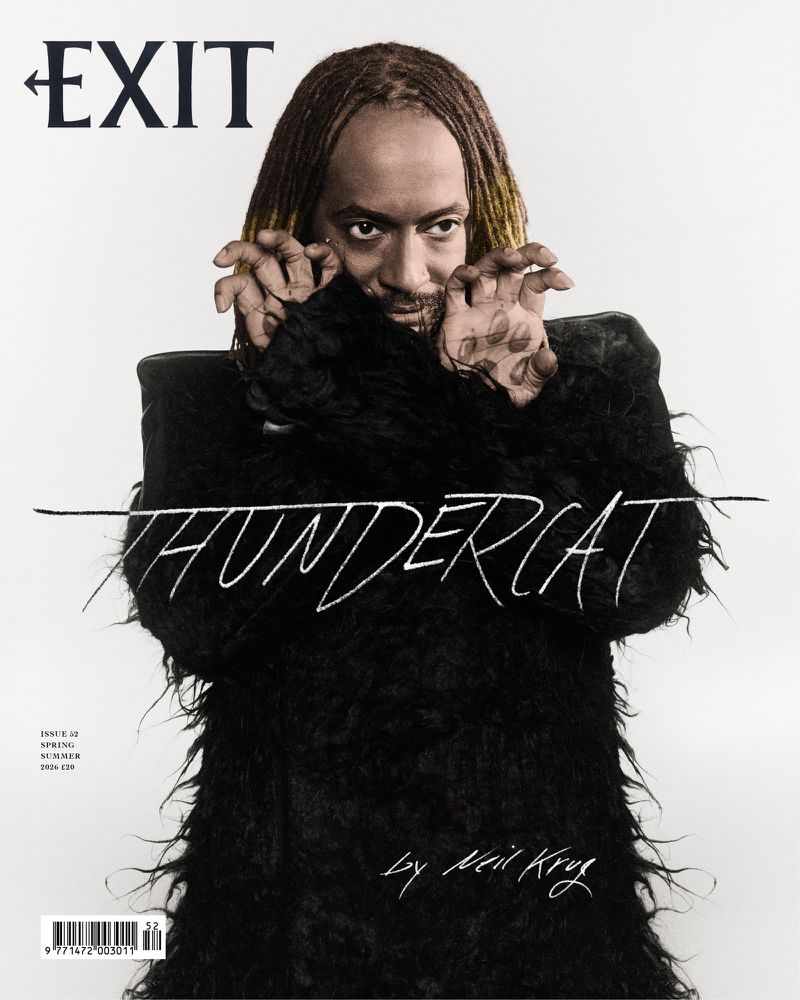 Thundercat posing in a textured black furry coat with clawed hands on the cover of Exit Magazine against a white backdrop.