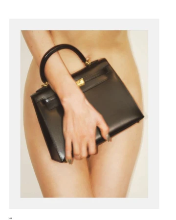 Jessica Stam holds a structured black leather handbag with gold hardware against her body in a fashion editorial.