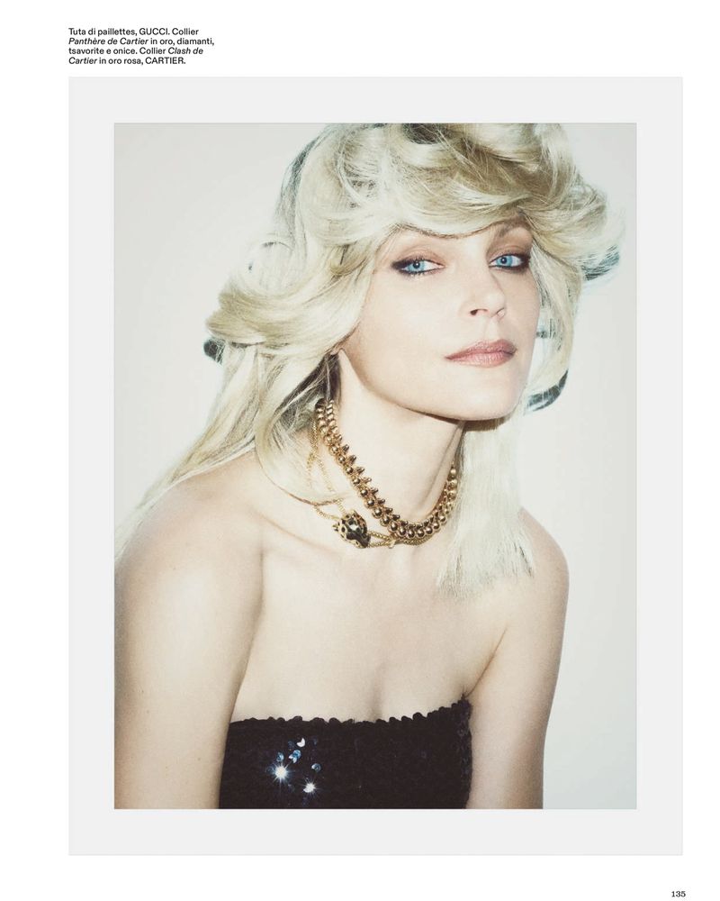 Editorial portrait of Jessica Stam with voluminous blonde hair wearing gold chain necklaces and a black strapless sequined top.