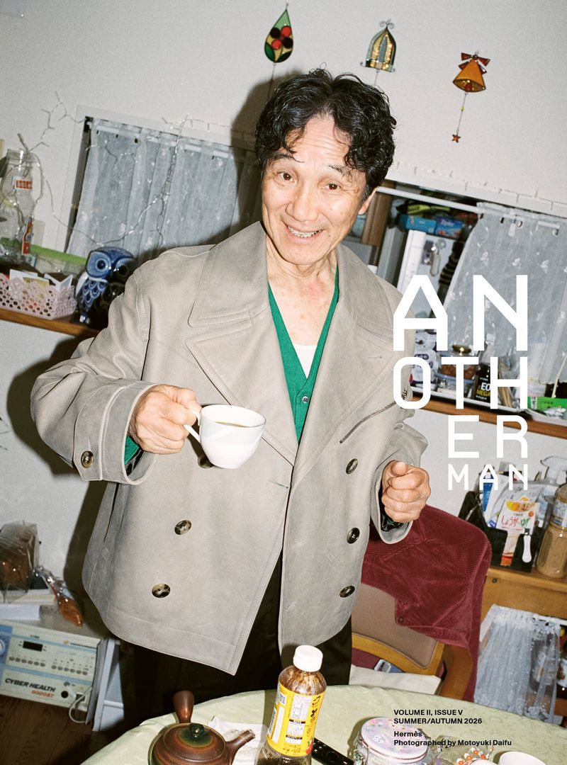 Magazine cover featuring an elderly Asian man indoors wearing a jacket, holding a cup, with various domestic objects in the background.