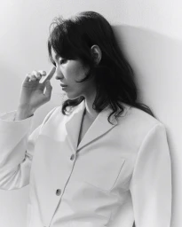 Model in a white blazer leaning against a plain light wall for the H&M Women Tailoring Lane project