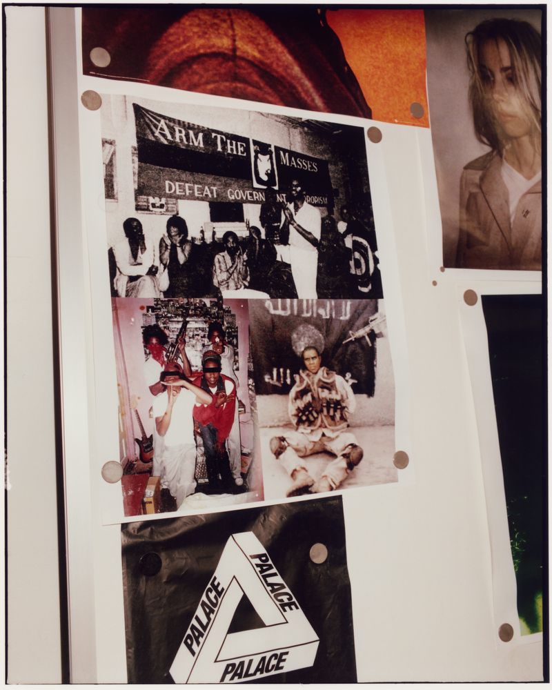 Collage of printed photographs and graphics pinned to a wall featuring political imagery and a Palace logo