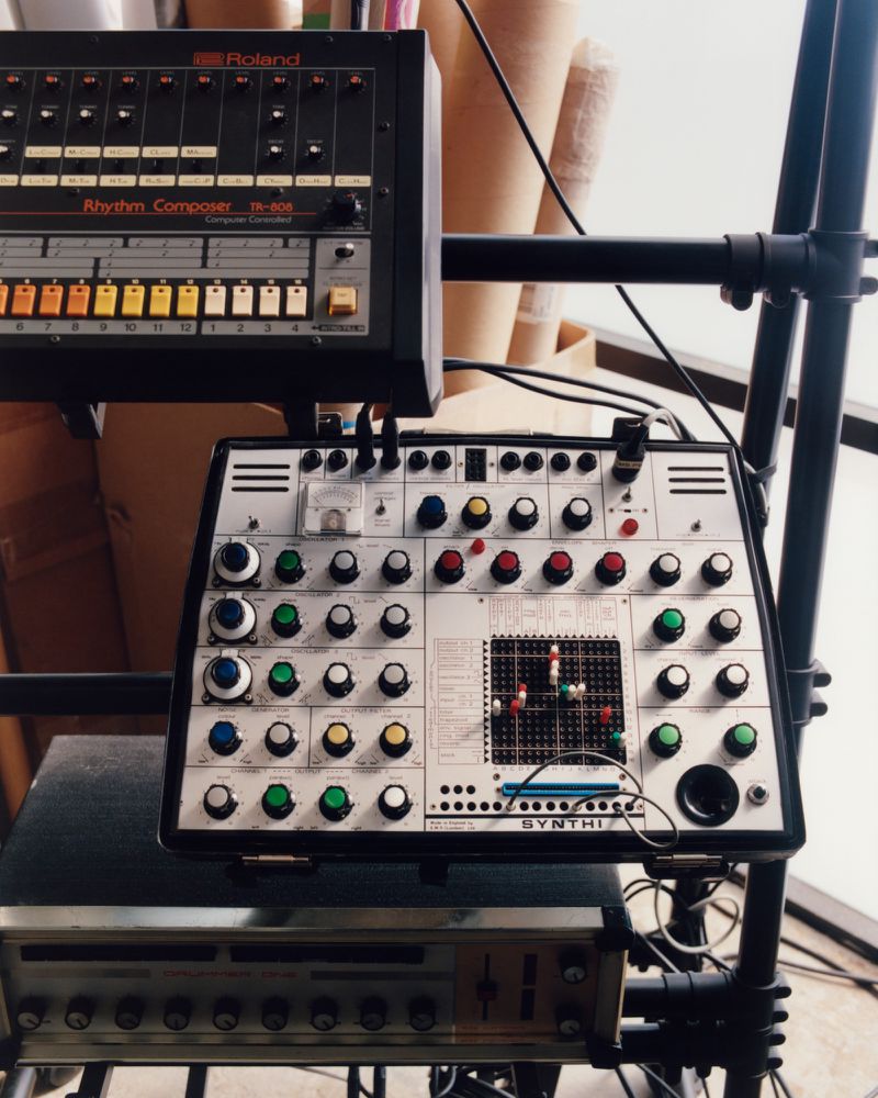 Vintage EMS Synthi synthesizer and Roland TR-808 drum machine mounted on a multi-tier studio rack.