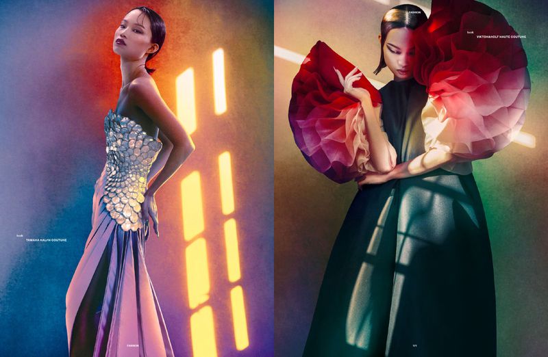 Model wearing sculptural high fashion garments posing against a richly colored gradient background with warm linear light patterns.