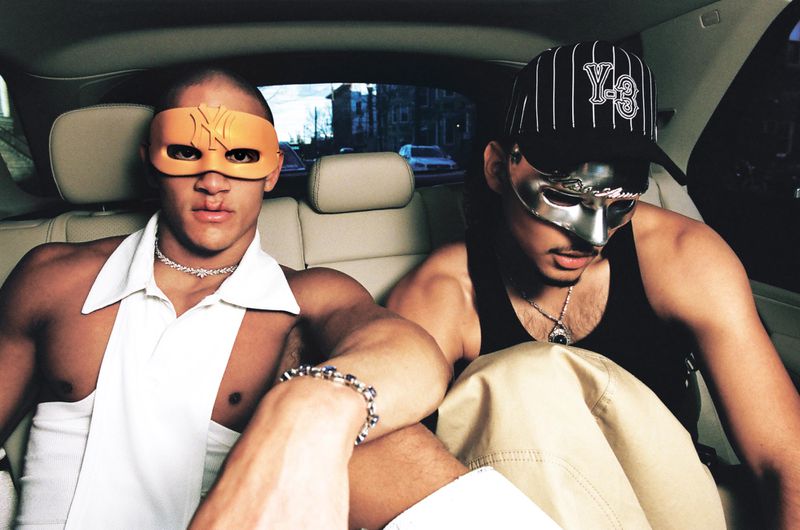 Two men wearing masks and accessories seated in the back of a car for an i-D Magazine editorial titled Masc Appeal.