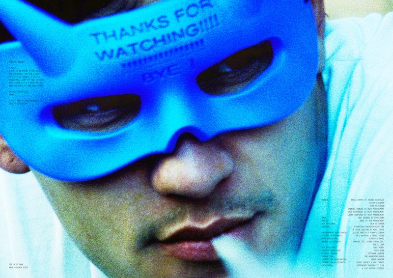 Close-up portrait of an adult male wearing a blue eye mask, with prominent facial features and a mysterious atmosphere enhanced by unique lighting.