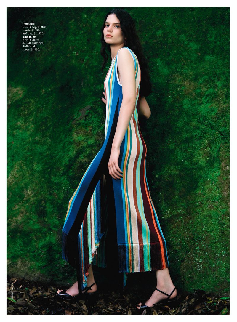 Model Hana Lubisz wearing a striped dress against a mossy green stone wall for Vogue Australia.