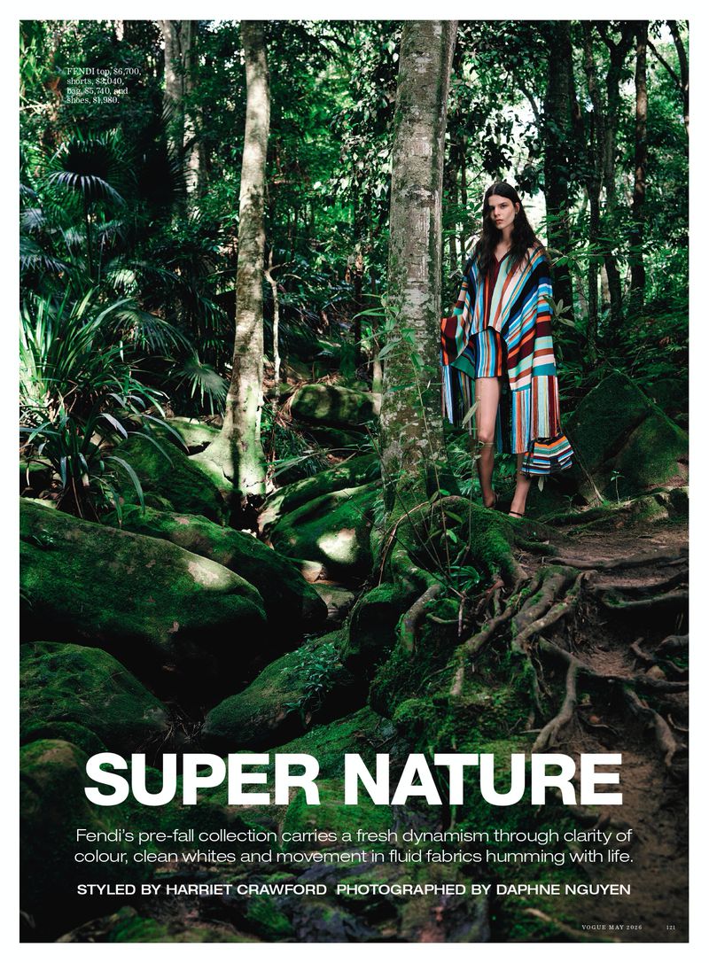 Model in striped poncho standing amidst lush mossy trees for Vogue Australia Super Nature editorial