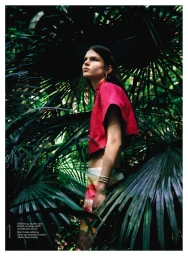 Model Hana Lubisz in a pink top posing amidst lush green palm fronds for the Vogue Australia Super Nature editorial project.