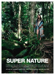 Model in striped poncho standing amidst lush mossy trees for Vogue Australia Super Nature editorial