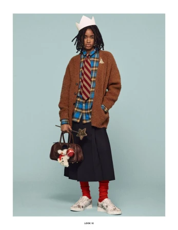 Adult wearing a brown cardigan, plaid shirt, skirt, sneakers and a paper crown, holding a handbag and a magic wand, on a blue background.