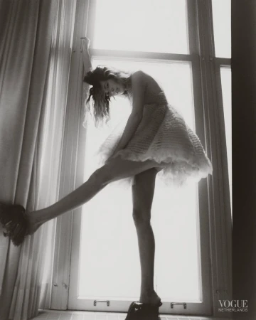 Model in a textured white dress standing on a windowsill against a bright window for Vogue Netherlands TILL STYLE DO US PART editorial.